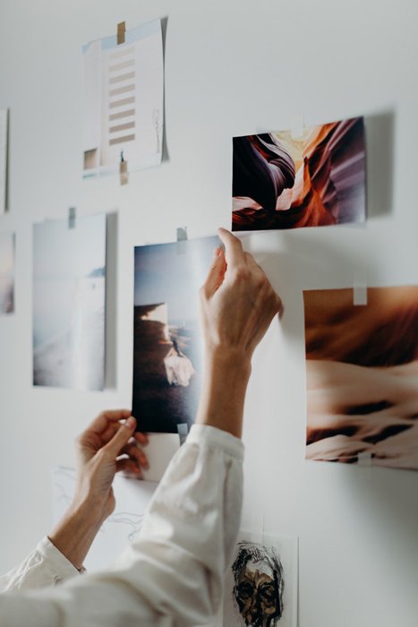 Una persona colgando impresiones fotográficas en una pared.