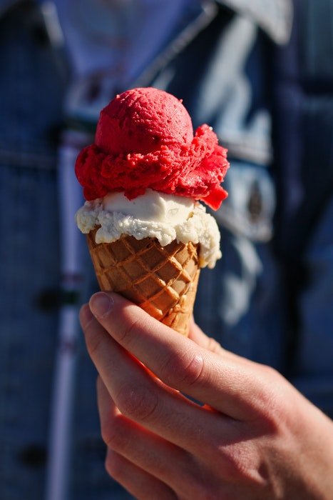 Un cono de helado de frambuesa y vainilla