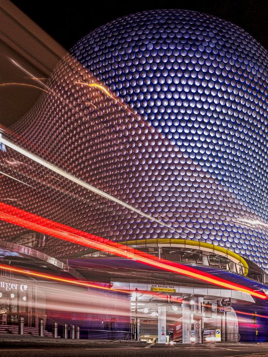 El Bullring Shop Center en Birmingham con las estelas de luz de un autobús de dos pisos que pasa por delante