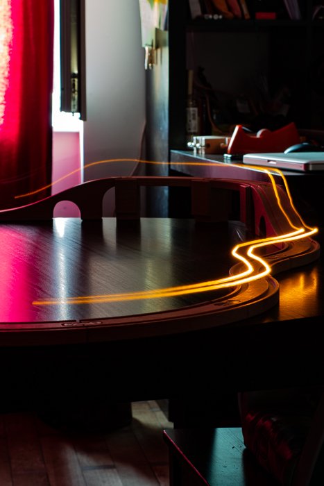 Estelas de luz amarilla de un tren de juguete con exposición prolongada