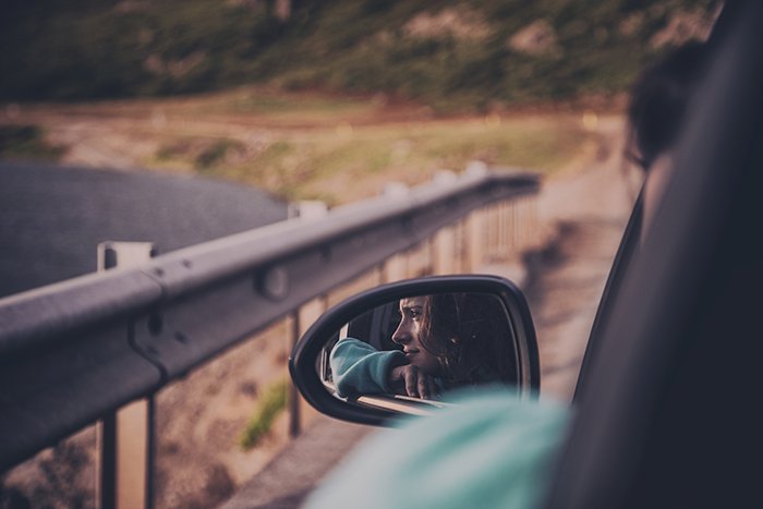 el reflejo de una mujer joven en el espejo lateral de un coche que conduce