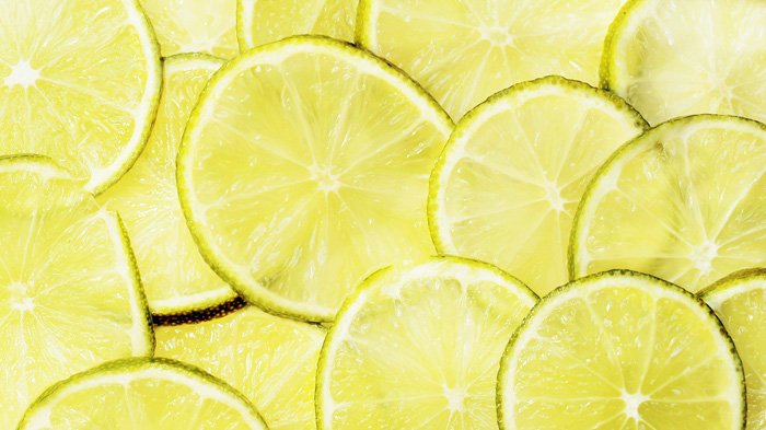 Una foto de cerca de limas en rodajas usando un esquema de color monocromático amarillo verdoso