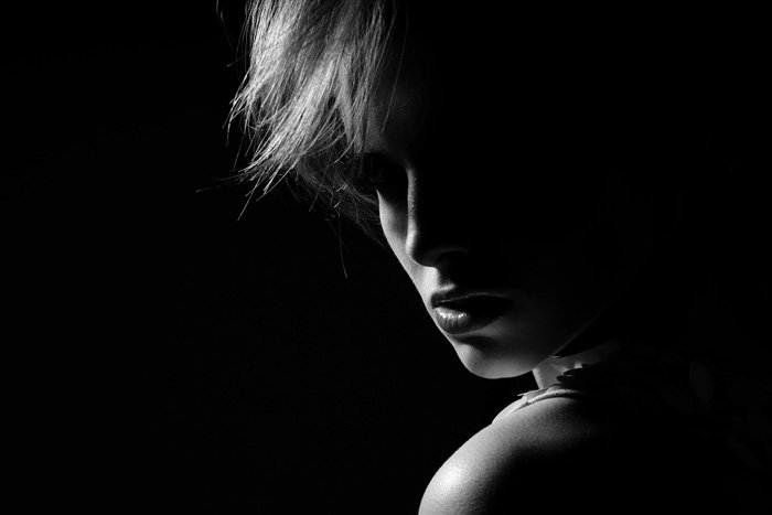 Retrato monótono atmosférico de una modelo femenina mirando malhumorada a la cámara