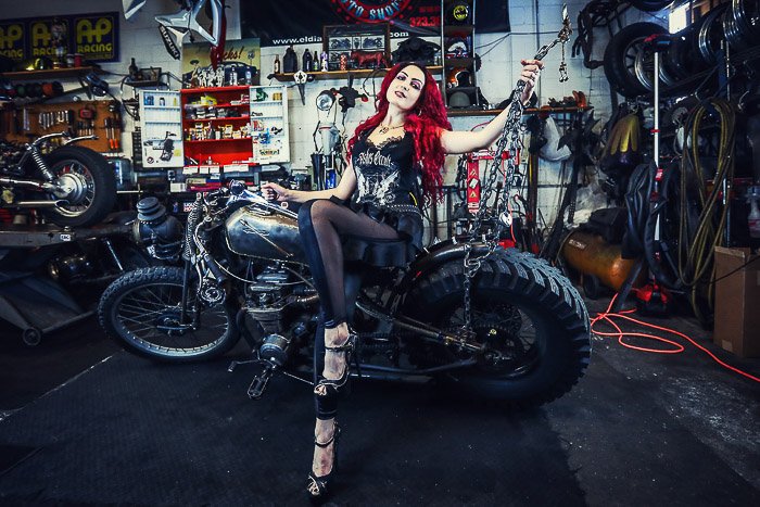Genial retrato de fotografía de motocicleta de una modelo femenina posando en una bicicleta