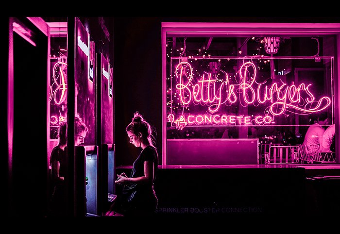 Un retrato de una modelo femenina rodeada de luces de neón de color rosa intenso.
