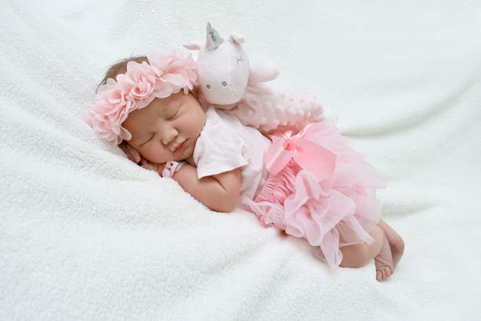foto de un bebé recién nacido con un lindo atuendo posado con un oso de peluche