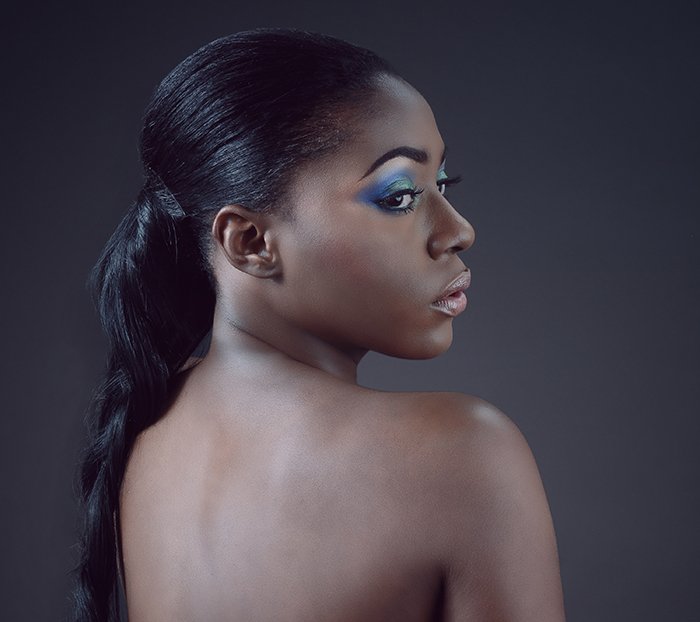 Fotografía de desnudo artístico de una modelo femenina contra un fondo gris suave