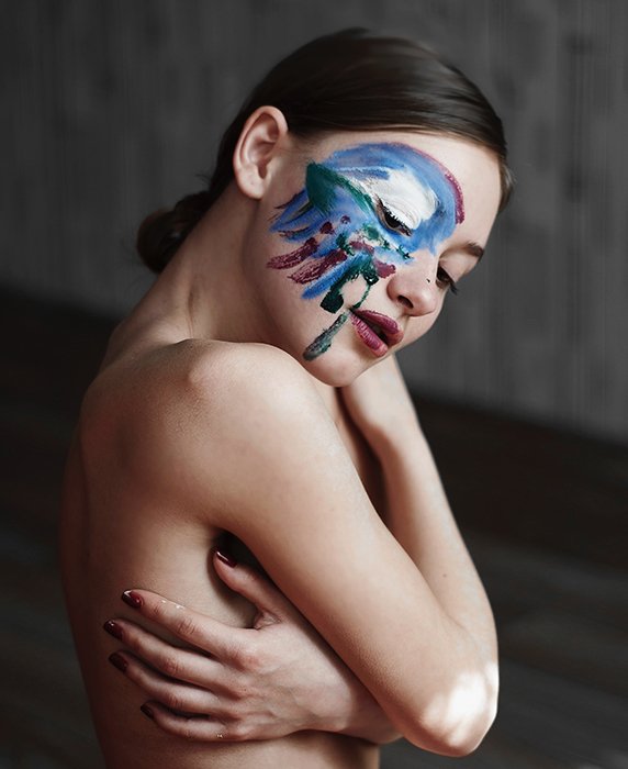 Fotografía de desnudo artístico de una modelo femenina con pintura en la cara