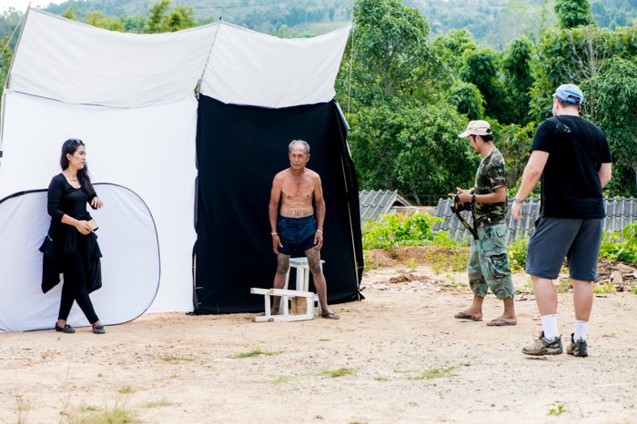 Un estudio de fotografía de retratos al aire libre instalado en un pueblo que muestra el difusor arriba, la tierra desnuda utilizada como reflector en el frente y el gran reflector desplegable.
