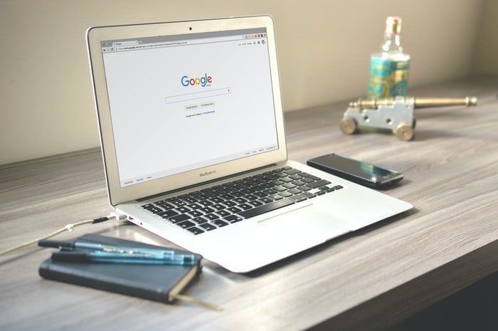 una imagen de un macbook pro en una mesa con google en la pantalla