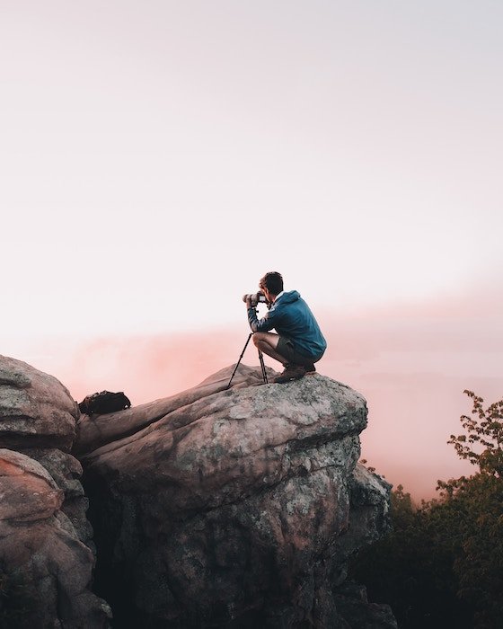 Un fotógrafo tomando una foto en un acantilado.