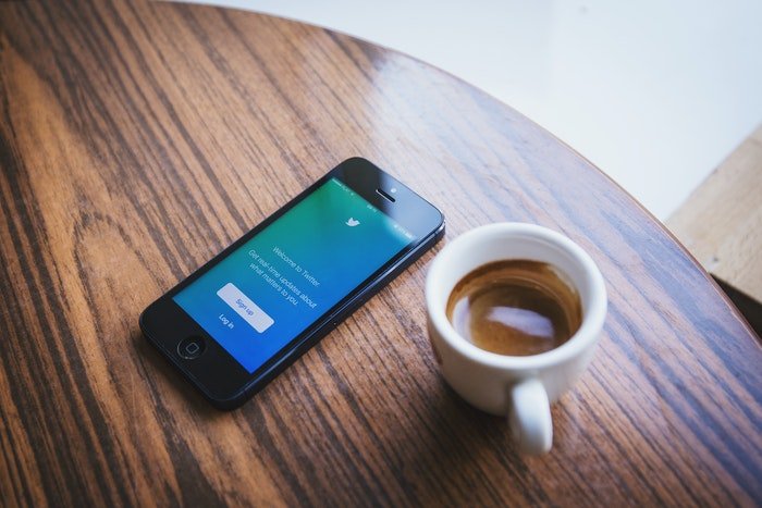 Un teléfono inteligente y una taza de café en una mesa