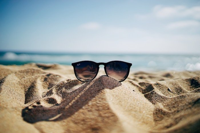 Foto de gafas de sol tomadas en la playa en la arena.