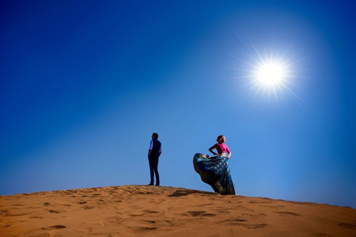 un impresionante retrato de una pareja posando en un desierto tomado con el flash Profoto b10