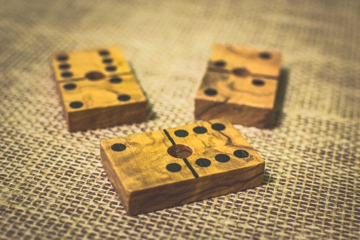 primer plano de tres fichas de dominó de madera sobre una mesa marrón usando la regla de composición de probabilidades