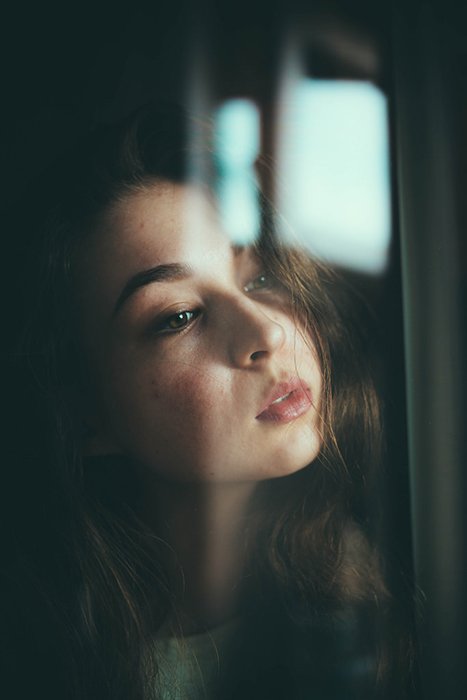 Retrato atmosférico de una modelo femenina mirando a través de una ventana: excelentes poses para selfies