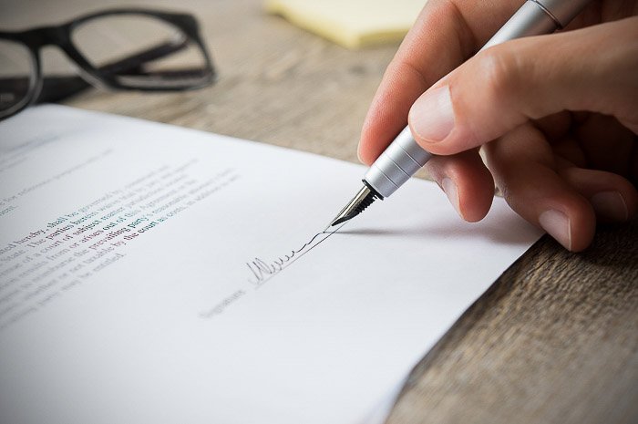 Un primer plano de un fotógrafo que firma un contrato para vender imágenes de archivo a un importante sitio web de acciones