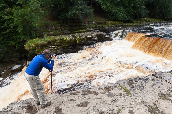 Un fotógrafo tomando una foto de una cascada: venda fotos en línea