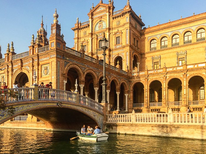Fotografía brillante de viajes de personas en un bote en un canal frente a un hermoso edificio