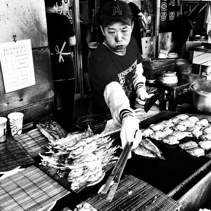 foto callejera en blanco y negro de un vendedor del mercado que fríe pescado