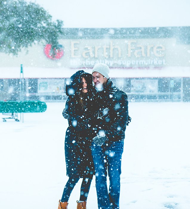 Cerrar la fotografía de retrato de invierno de una pareja posando en la nieve que cae