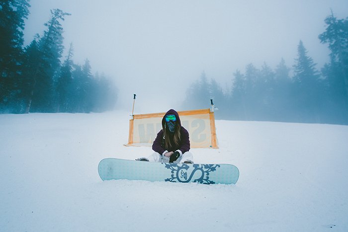 Retratos de nieve atmosférica de una snowboarder posando en un paisaje invernal