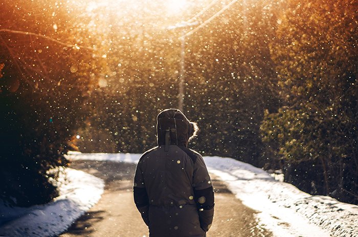 Atmospher invierno retrato de un modelo caminando por una carretera bajo la nieve que cae