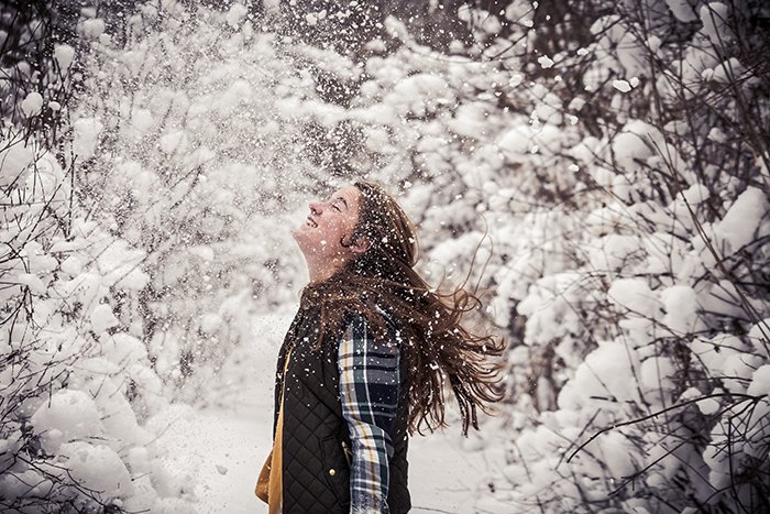 Divertido retrato de nieve de una modelo femenina riendo y jugando en la nieve