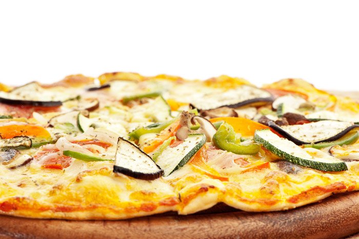 Primer plano de una pizza vegetariana recién hecha tomada con un softbox directamente detrás del sujeto.