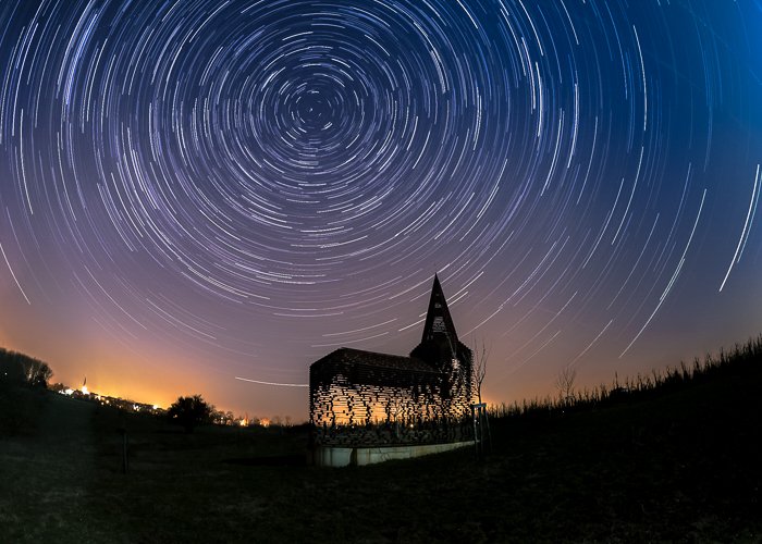 Silueta de la Iglesia See Through iluminada cálidamente desde atrás, bajo el cielo nocturno lleno de estrellas