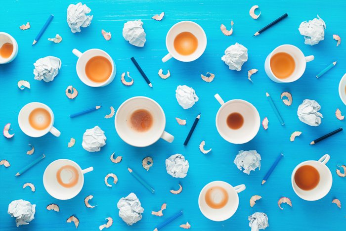 Ideas creativas de fotografía de bodegones con tazas de café vacías, bolas de papel arrugadas y virutas de lápiz sobre un fondo azul colorido.  Concepto de inspiración minimalista.