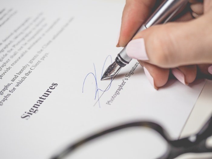 Un primer plano de una persona que firma un contrato de fotografía de archivo