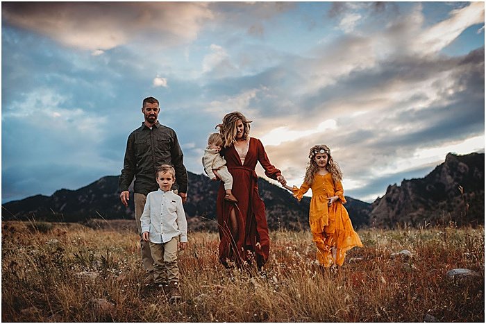 Foto de una familia caminando en un campo con montañas al fondo.
