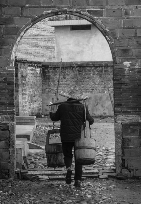 imagen en blanco y negro de un hombre con gorra caminando por un arco