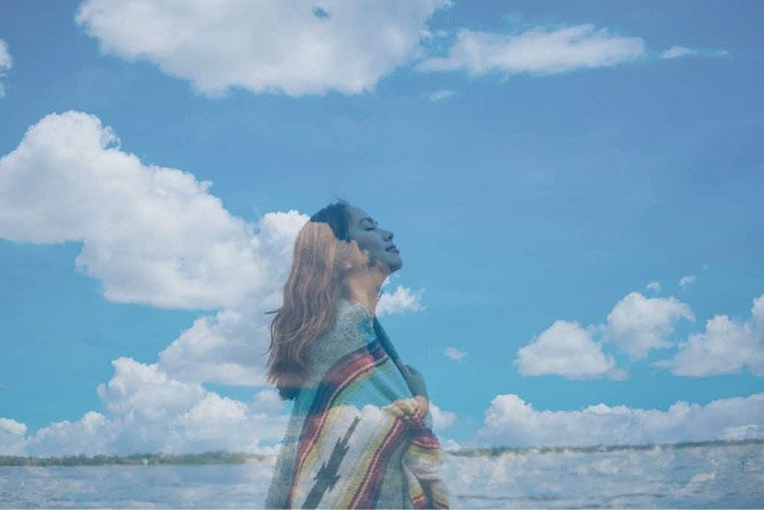 Foto de ensueño de una niña superpuesta con una imagen de nubes esponjosas