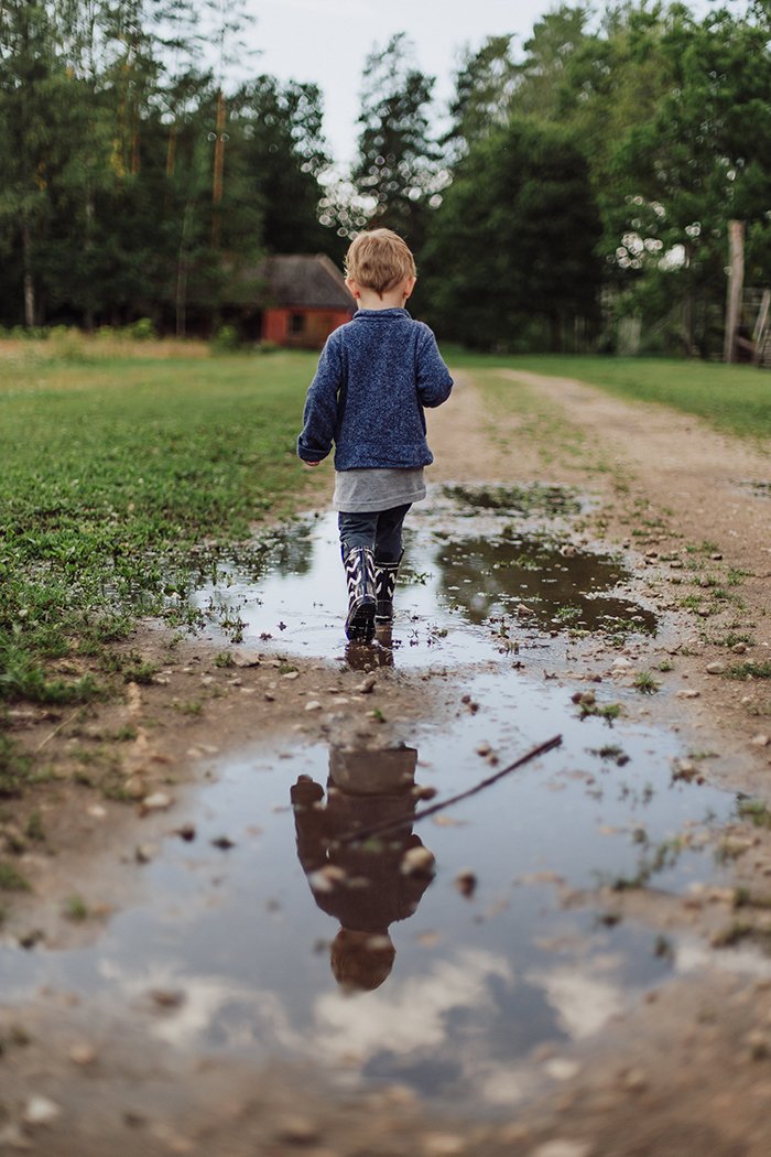 Foto de un niño con botas caminando por un camino de tierra
