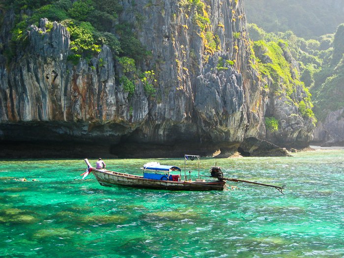 barco de madera en aguas verdes cristalinas en Tailandia