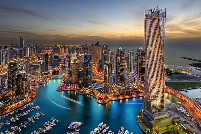 Paisaje urbano de los Emiratos Árabes Unidos al atardecer, iluminado por luces doradas, aguas azules profundas del arroyo