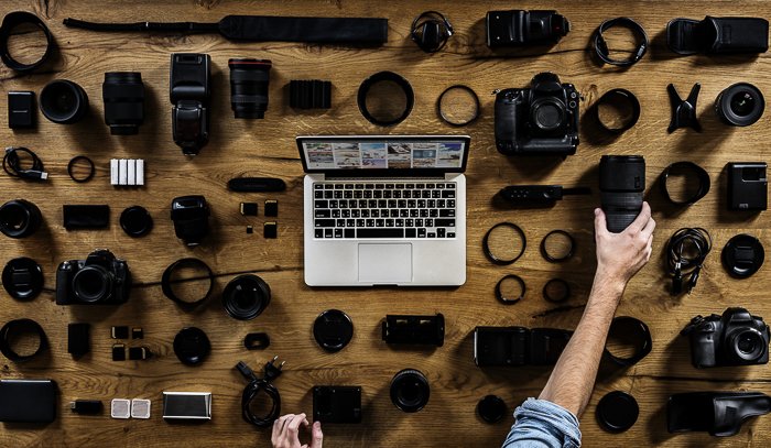 Vista aérea de una computadora portátil en la mesa rodeada de diferentes accesorios de cámara