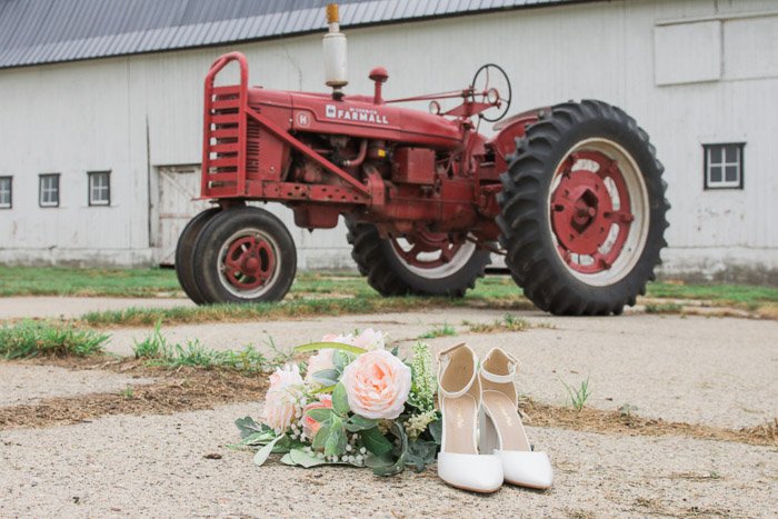 Fotografía de boda humorística bodegón de accesorios de boda en el suelo frente a un tractor rojo