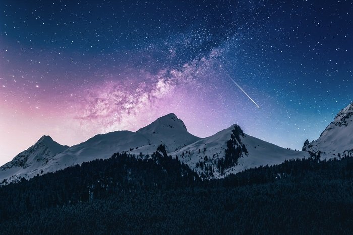 una imagen teñida de púrpura y azul de una galaxia sobre las montañas usando un filtro de astrofotografía ND