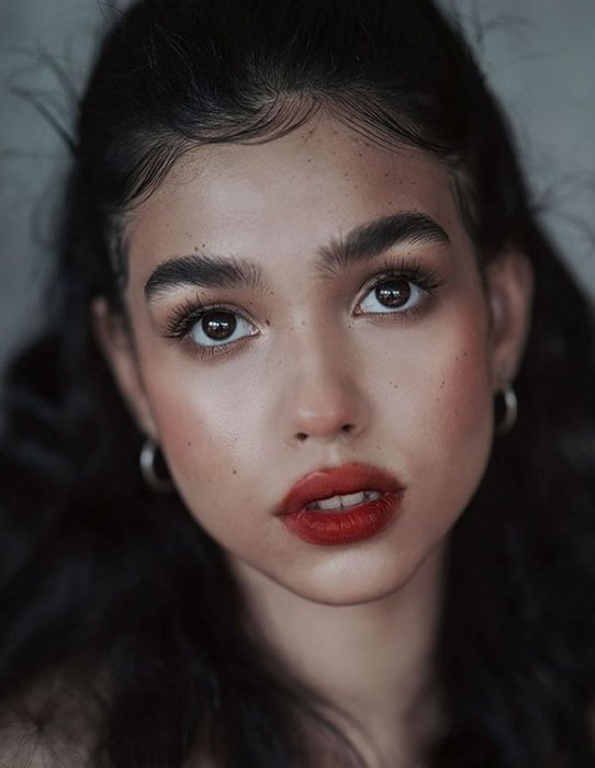 Cerrar retrato de niña con cabello oscuro, ojos marrones y labios rojos