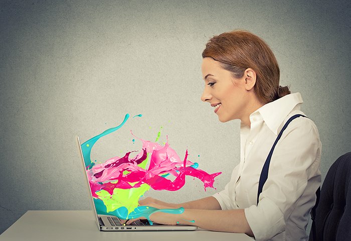 Perfil de vista lateral atractiva mujer de negocios joven feliz que trabaja en la computadora portátil salpicaduras de colores que salen de la pantalla efecto líquido aislado fondo de pared gris.  Visión de expresión facial positiva