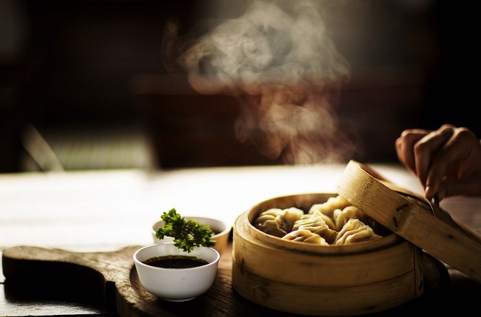 Accesorios de fotografía de alimentos: sumerja en un tazón pequeño y albóndigas en un recipiente de bambú con vapor saliendo de ellos
