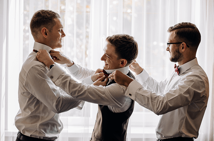 Consejo fotográfico para padrinos de boda: una foto de tres padrinos de boda preparándose