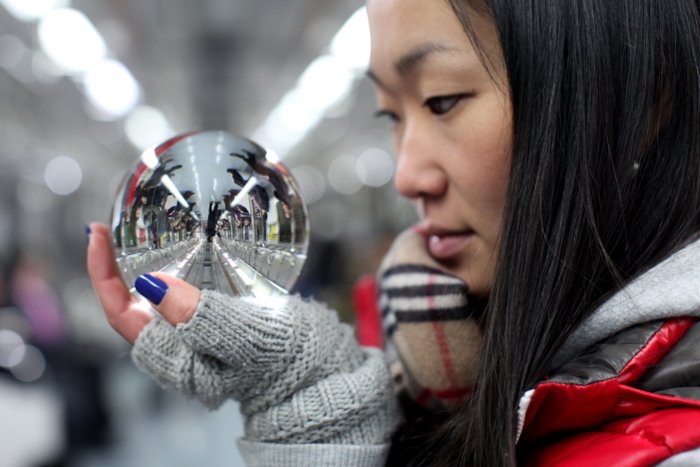 Un retrato de una modelo femenina sosteniendo una bola de cristal que refleja el interior de un tren