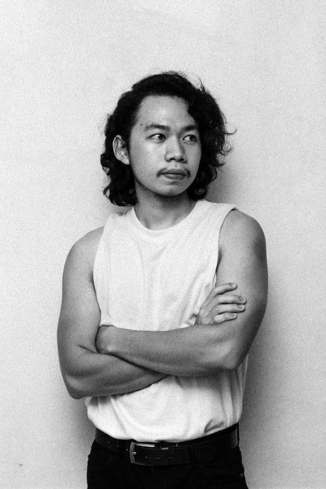 pose masculina de un hombre en la parte superior del tanque con los brazos cruzados mirando hacia otro lado