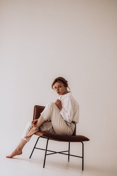 Mujer sentada en una silla con una pierna hacia arriba como idea para poses de modelo