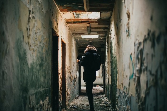 exploración urbana: un fotógrafo caminando por un pasillo oscuro en un edificio abandonado