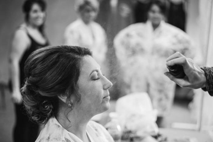 foto de boda en blanco y negro de la novia maquillándose con las damas de honor en el fondo